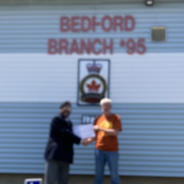 Comrade Rob Pitcher presents mending on the Fly organizer, Ray McEachern with a cheque for $1500